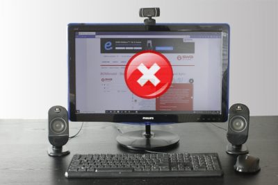 Ein Computerbildschirm steht auf dem Schreibtisch. Auf dem Bildschirm ist eine Webseite zu sehen. Über der Webseite wird ein Fehlersymbol angezeigt.